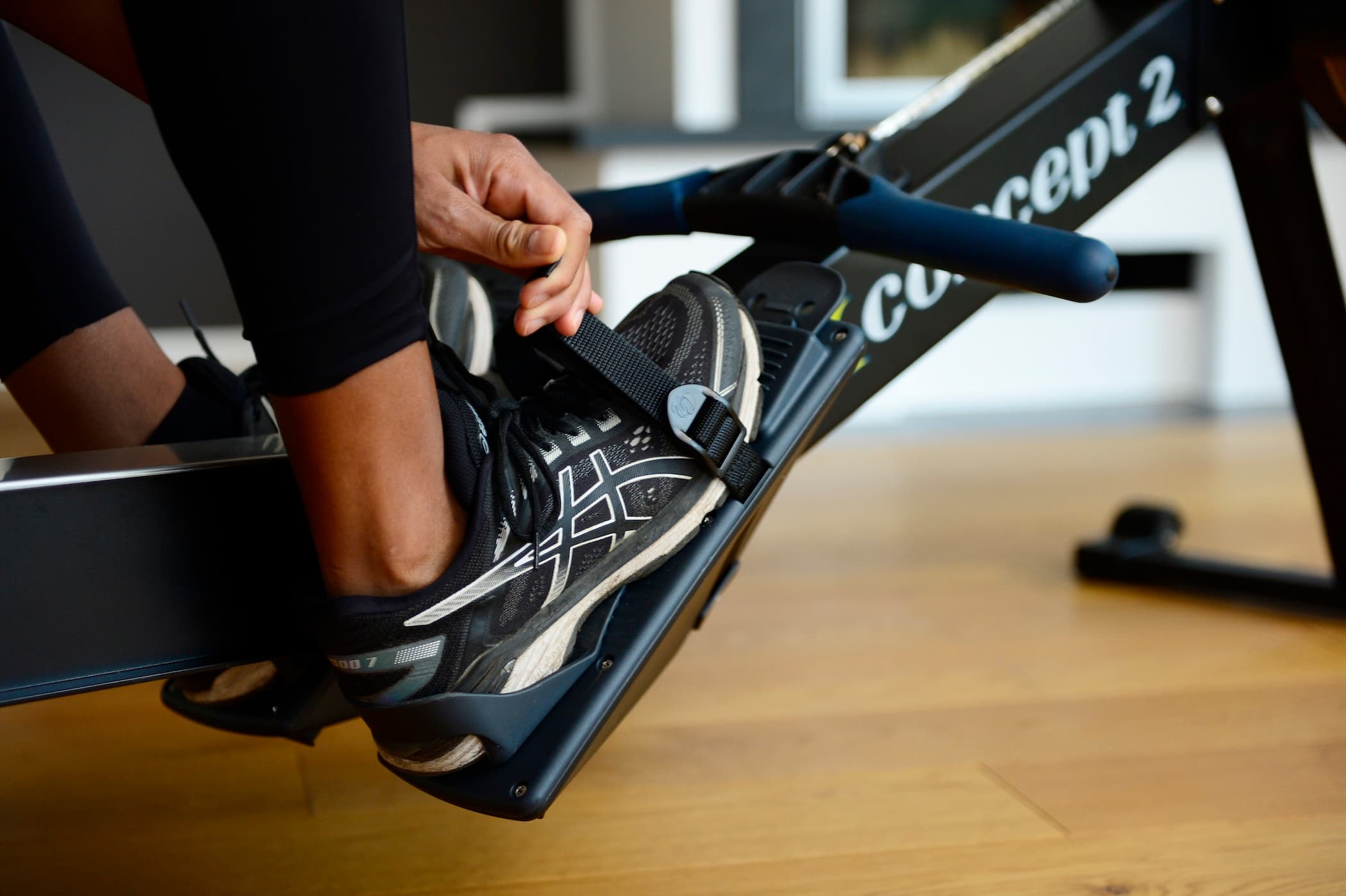 Someone tightening the footstraps on a RowErg